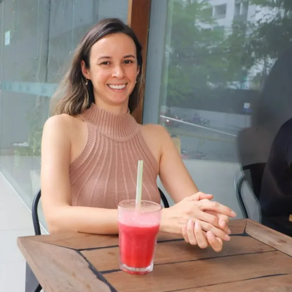 Cliente sorrindo à mesa do Salatta com um suco natural