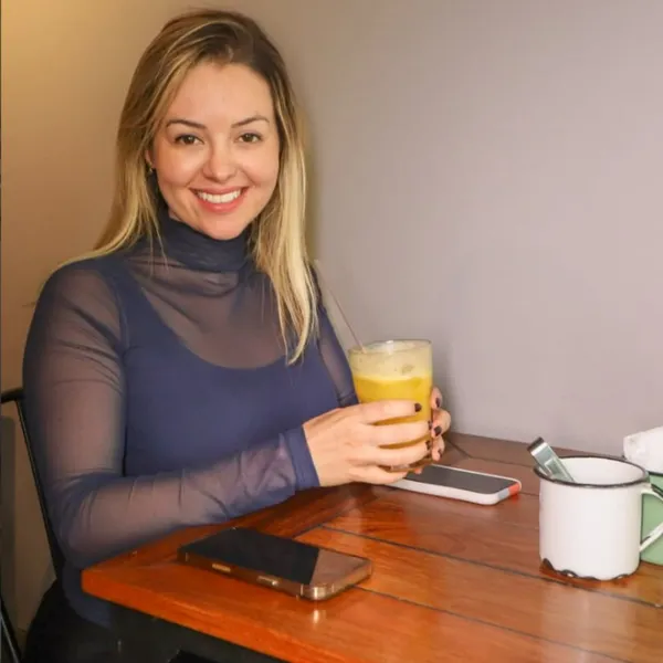Cliente sorrindo com um copo de suco de laranja no Salatta
