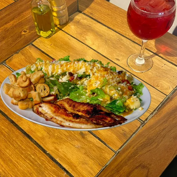 Prato com peixe grelhado, salada e taça de suco no Salatta