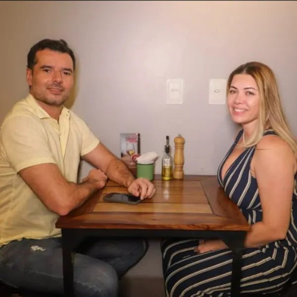 Casal sorrindo à mesa do salão do Salatta em Caruaru